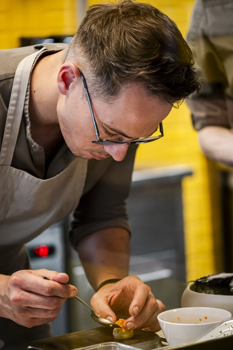 Chef Michiel van Laere maakt een gerecht af in de keuken