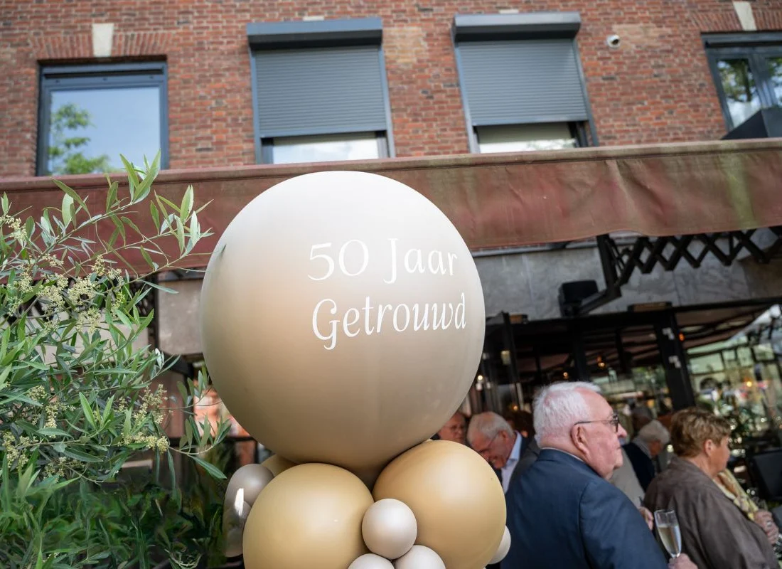 Ballon met 50 Jaar Getrouwd voor de gevel, gasten met een glas