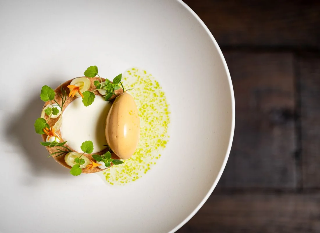 Dessert met panna cotta, ijs en kruidenolie op een wit bord