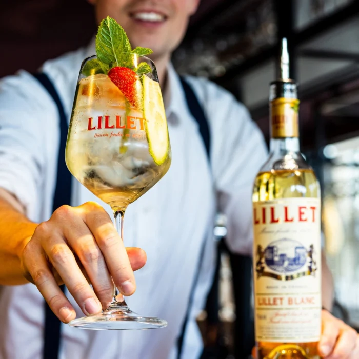 Barman reikt een cocktail met munt en aardbei aan