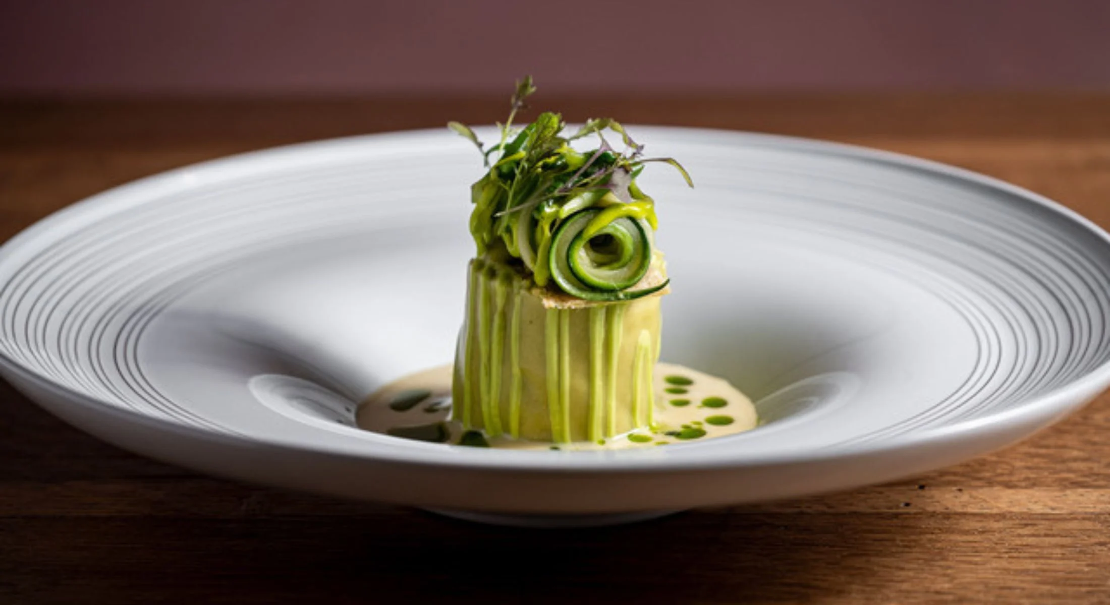 Courgetterol met kruiden en kruidenolie in een wit bord, recht van voren